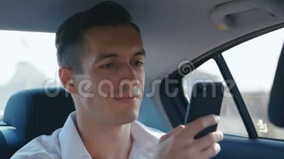 年轻的商人在开车时使用他的智能手机男人正在检查指甲帽子或新衣服视频的预览图