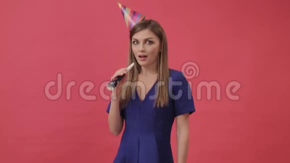 积极的女人戴着生日帽吹着派对哨子紫色背景工作室视频的预览图