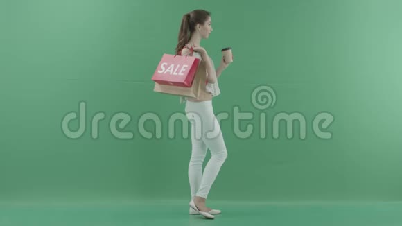 快乐的女人喝着咖啡在绿色屏幕上侧写购物后拿着袋子视频的预览图