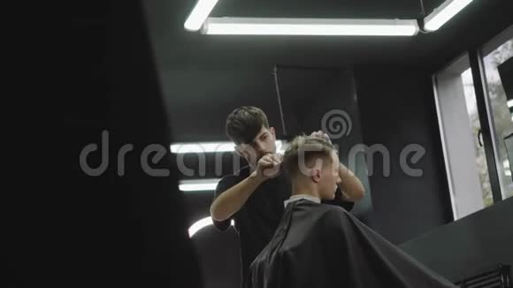 理发师用剪刀剪客户的头发有魅力的男性正在理发店理发手持视频的预览图