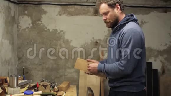 一个留着胡子和胡子的木匠用锯子锯了一个木制的东西手里拿着它损坏了一根手指视频的预览图