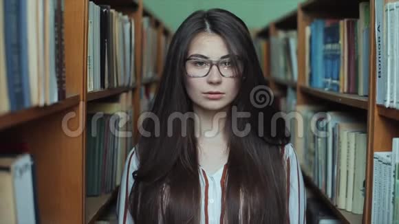 图书馆里漂亮女孩的肖像留着长长的黑发女学生在一大堆书中学习视频的预览图