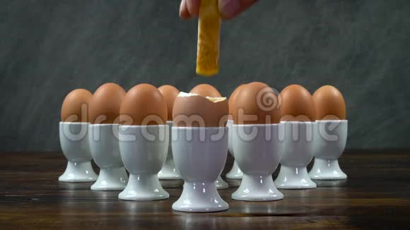 把一个土司士兵端成一个煮鸡蛋放在一张木桌上的一组鸡蛋里视频的预览图