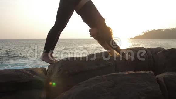 身穿黑色运动服的女士站在岩石悬崖上做瑜伽姿势视频的预览图