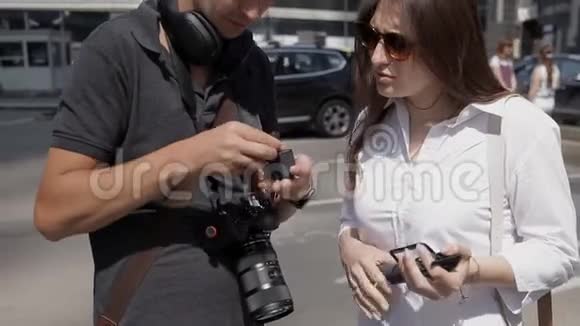 两个旅行者一个男人和一个女人在市中心的一个动作摄像机里更换电池视频的预览图