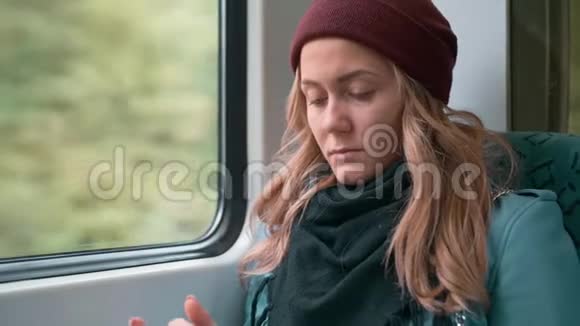 年轻孤独的白种人心烦意乱的女孩戴着红帽子乘坐地铁或电车用电话打印一条信息慢慢视频的预览图