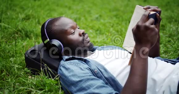 非裔美国人躺在草地上手里拿着书视频的预览图