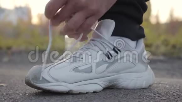 年轻白种人的贴身鞋带秋天户外运动的人穿着白色运动运动鞋视频的预览图