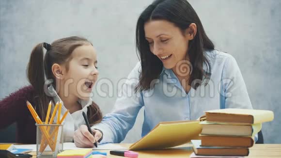 坐在桌子旁的漂亮女学生在家和她妈妈做作业视频的预览图