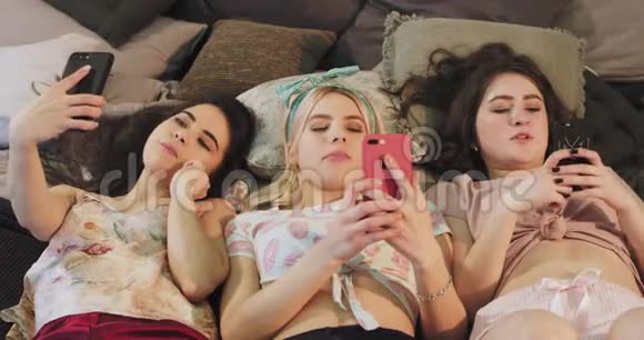 漂亮的少女们一边躺在床上一边吃着泡泡糖一边穿着睡衣和视频的预览图