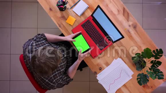 年轻的白种人商人在平板电脑上滚动的特写镜头屏幕前放着绿色的彩色键盘视频的预览图
