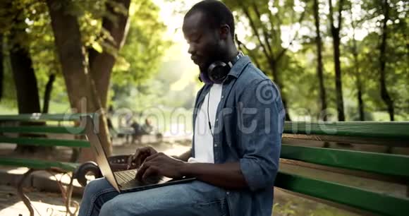 男子在公园夕阳下的膝上工作视频的预览图