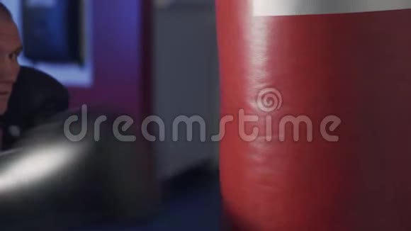 关闭用拳击手套踢在拳击袋上慢动作拳击训练视频的预览图