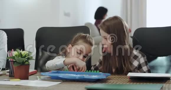 非常有魅力的孩子两个女孩和一个男孩和他们成熟的母亲在桌子上玩得很开心他们在画视频的预览图
