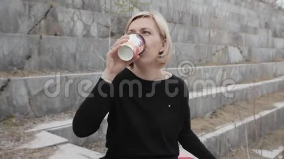 美丽的女人在大理石背景上喝咖啡废弃的大理石矿床视频的预览图