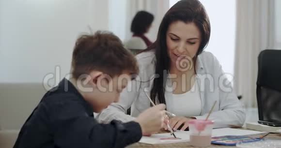 在现代的房子里一个成熟的母亲和她的孩子一起做家庭作业和一些手工艺时间背景视频的预览图