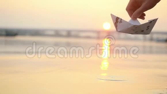 在美丽夕阳西下的海面上人类的手在水面上展开纸船把它推开视频的预览图