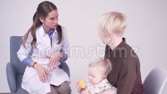 妈妈和一岁的女儿在医生办公室儿科医生做笔记视频的预览图