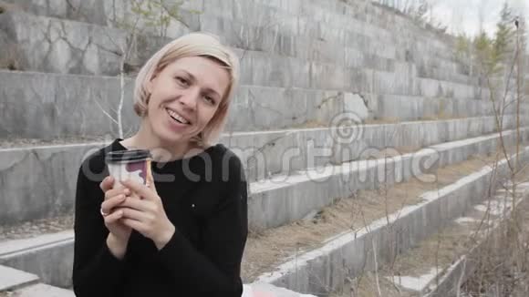 美丽的女人在大理石背景上喝咖啡废弃的大理石矿床视频的预览图