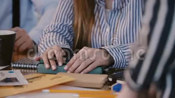特写镜头白种人女性办公室工作人员的手在铅笔盒上与同事一起在团队会议上工作视频的预览图