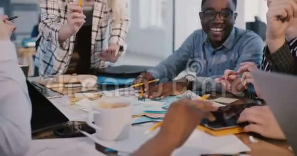 中镜头的多民族创意营销团队在桌后进行头脑风暴黑人员工微笑视频的预览图