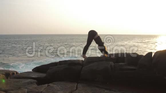 身穿黑色运动服的女士站在岩石悬崖上做瑜伽姿势视频的预览图