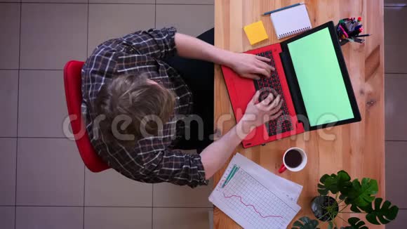 一位年轻的高加索商人用绿色屏幕在笔记本电脑上工作并提醒人们注意一件事视频的预览图