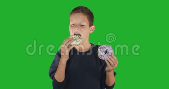 特写镜头一个有趣的家伙吃五颜六色的甜甜圈的肖像表达饮食概念底色4k视频的预览图