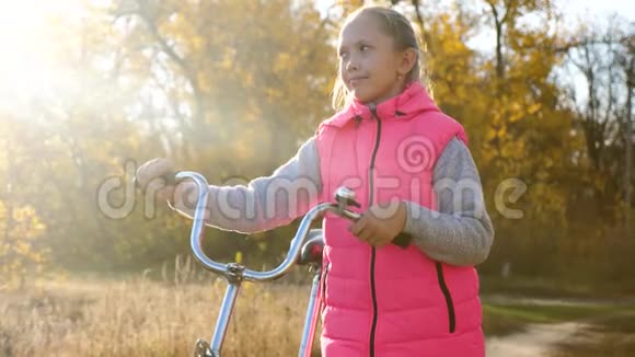 孩子们在公园里骑自行车旅行年轻女孩走路一个年轻女孩沿着马路散步骑自行车视频的预览图