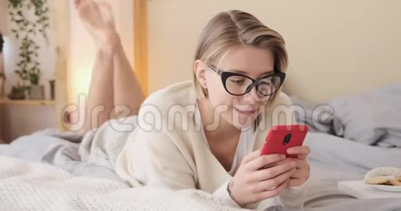 令人震惊的女人在床上用手机视频的预览图