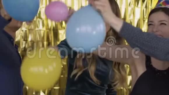 在一个聚会上快乐的人戴着纸节日的帽子打气球一群笑的混血儿在视频的预览图