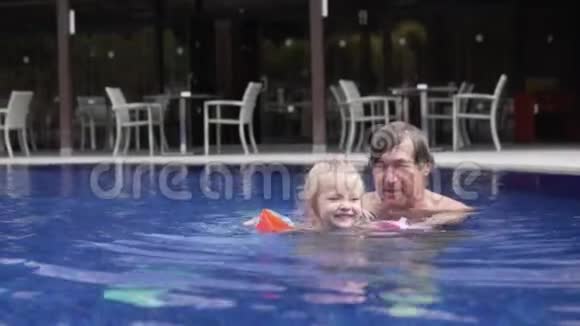 爷爷和他的小孙女正在游泳池里游泳视频的预览图