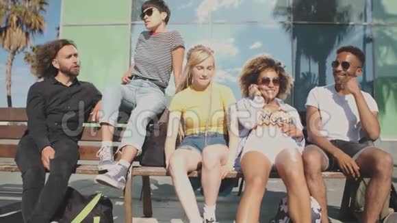 在夏日的长椅上快乐的现代朋友视频的预览图