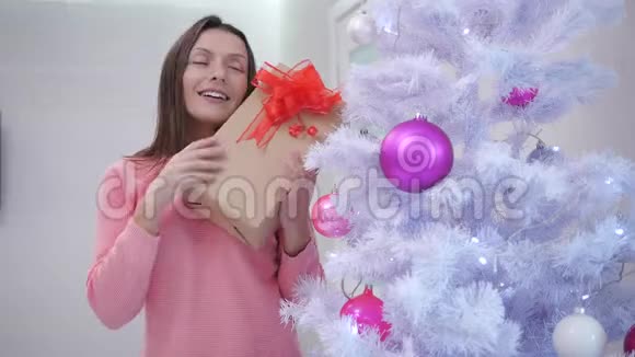 快乐的妈妈在圣诞树下为自己找到了一份礼物非常喜欢它感到感激视频的预览图