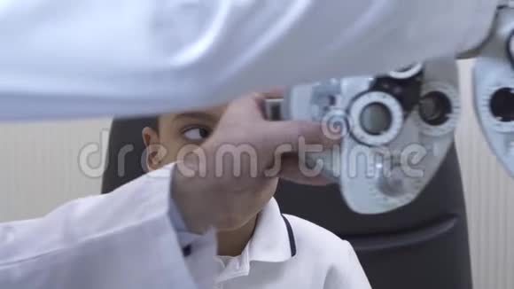 小男孩眼科医生用光翅目近距离检查眼睛医生在白人医疗中的双手视频的预览图