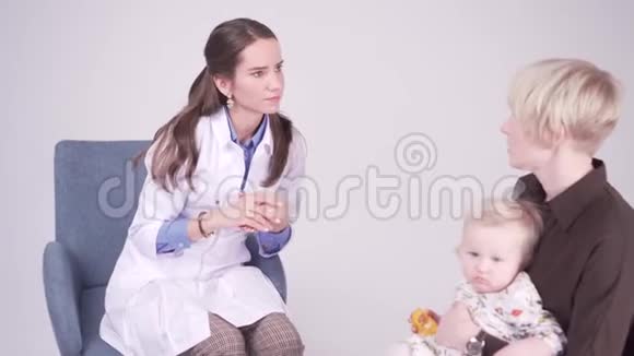 妈妈和一岁的女儿在医生办公室儿科医生做笔记视频的预览图