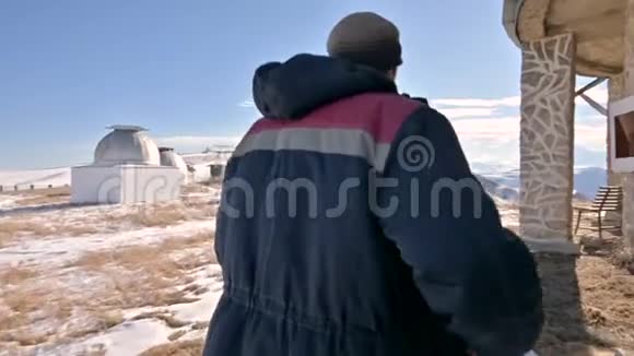 一位穿着牛仔裤和保暖制服的男性研究员在冬天阳光明媚的白天在雪地里行走视频的预览图