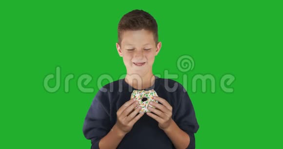 特写镜头一个有趣的家伙吃五颜六色的甜甜圈的肖像表达饮食概念底色4k视频的预览图