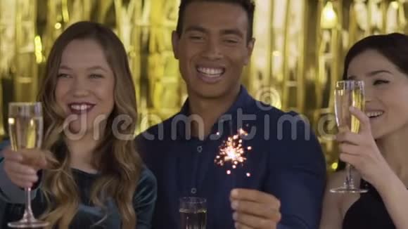在一个聚会上快乐的人带着一瓶酒闪闪发光一群笑的混血儿在视频的预览图