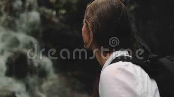女徒步旅行者靠近飞溅瀑布肖像视频的预览图