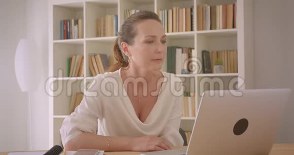 在办公室室内电脑上播放视频的白种人深色头发的女商人的特写照片视频的预览图