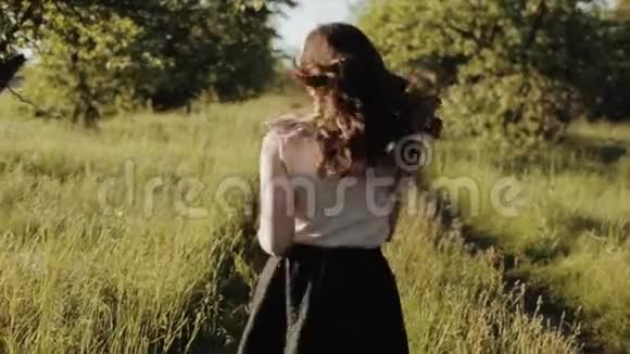 美丽的年轻女孩穿着黑色的裙子波浪般的头发在森林里奔跑笑着旋转她是视频的预览图