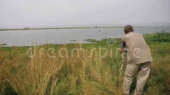 博物学家用相机拍摄湖中野河马的照片视频的预览图