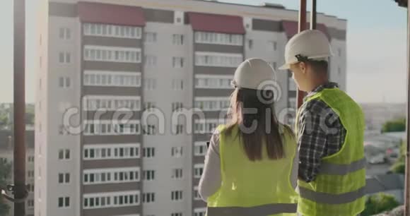 建筑工人在施工现场工作建筑工人看蓝图背面视图复制空间建筑物视频的预览图