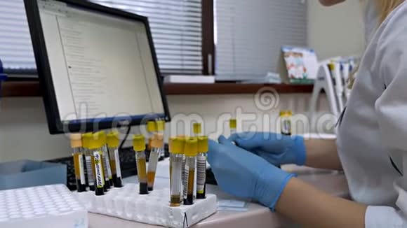 一位女科学家分析试管中的液体并将观察结果写入她的计算机科学家在视频的预览图