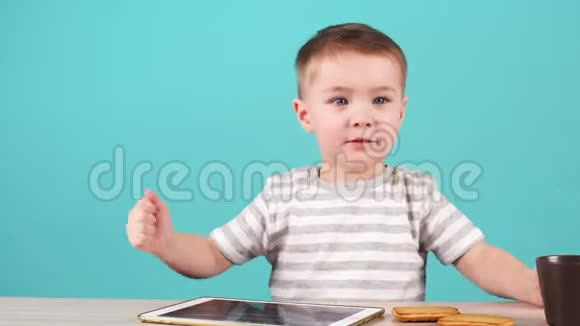 可爱的小男孩心情愉快坐在桌子前摆姿势拍照视频的预览图