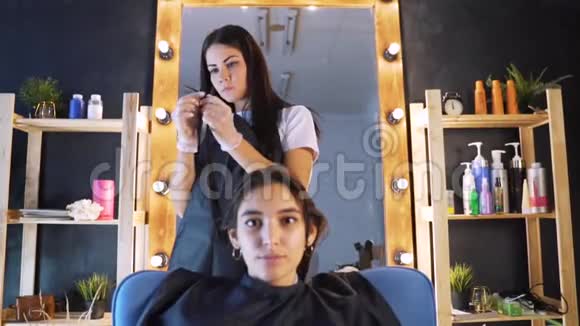 理发师发型师为女性客户梳头并使用理发师在专业美发店理发视频的预览图