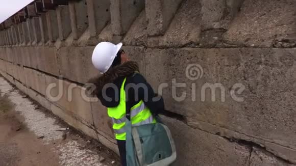 女检查员在混凝土墙附近检查和行走视频的预览图