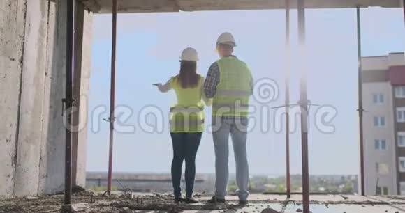 建筑工人在施工现场工作建筑工人看蓝图背面视图复制空间建筑物视频的预览图