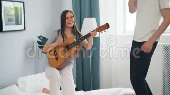 女孩和男人在公寓里弹吉他跳舞视频的预览图
